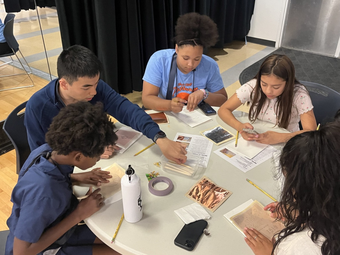 A diverse group of middle-school students works together at a table on a hands-on Pathways program activity.